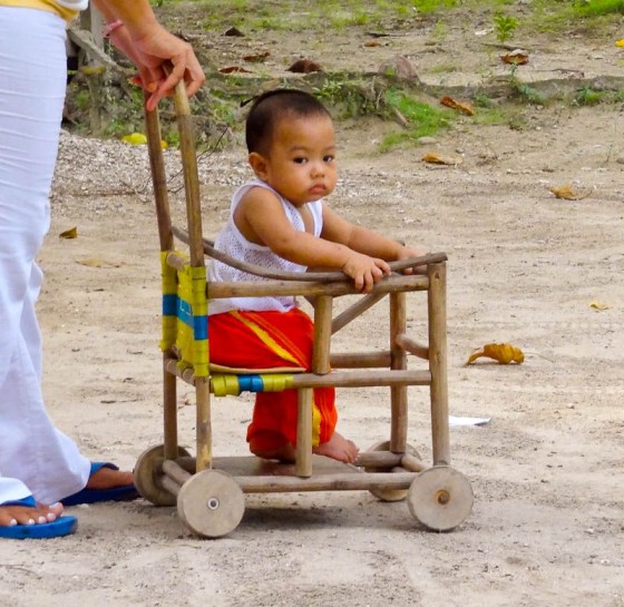 little boy in wooden stroller